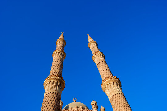 Majestic minarets of a traditional mosque rising against a clear blue sky