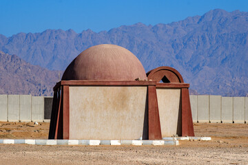 Unique desert architecture with a rounded dome structure against rugged mountain ranges © Buğra Kaan Ersoy