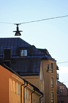Suspended Street Lanterns along Historic Residential Rooflines in Sodermalm Stockholm Sweden, Warm Sunlight on Pastel Facades Nordic Cityscape