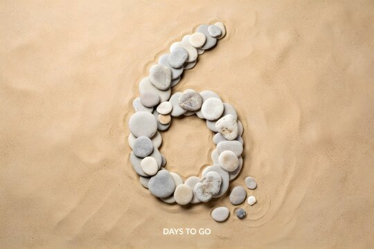 Number six made of smooth sea stones on sand background for countdown concept