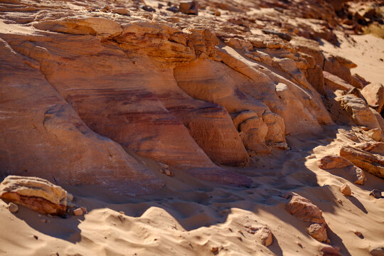 Rugged desert sandstone rock formation with weathered textures and sandy slopes