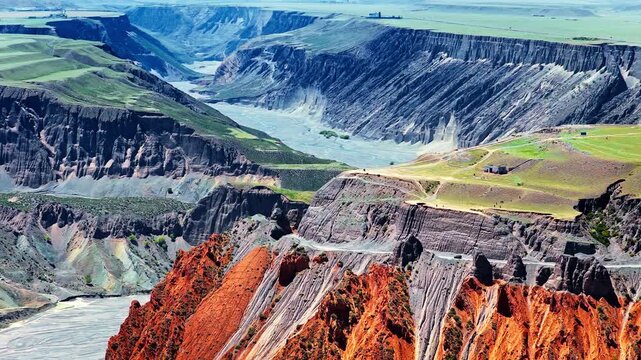 Aerial view of a remote dirt road on a steep eroded canyon cliff with a vehicle driving in a rugged mountain landscape in Anjihai Grand Canyon, Xinjiang, China
