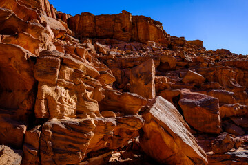 Massive sandstone boulders and textured rock formations in a dramatic desert canyon landscape © Buğra Kaan Ersoy