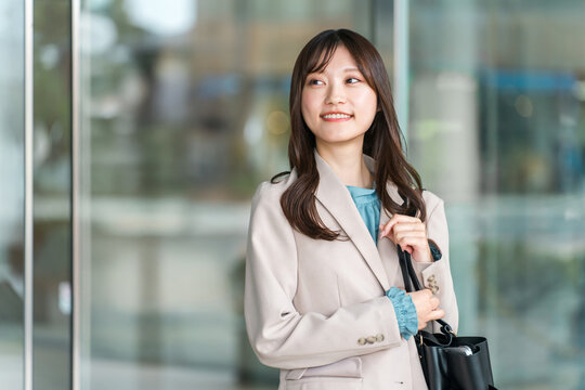 A young Asian businesswoman walking through a city office district.