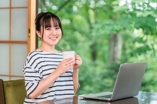 A freelance woman taking a break from workation, working from her accommodation, and drinking coffee during her break.