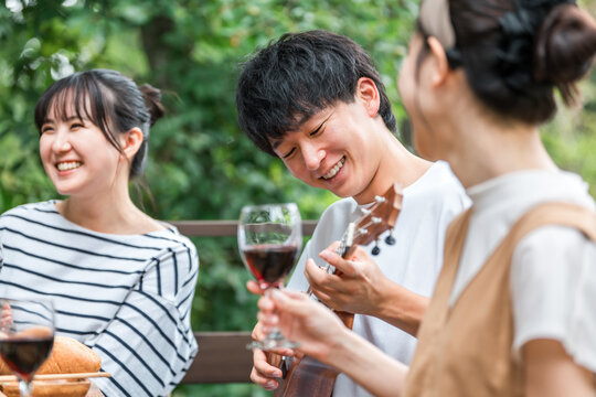 Young Asian men and women, friends, colleagues, and coworkers enjoying a barbecue, home party, and glamping on a wooden deck.