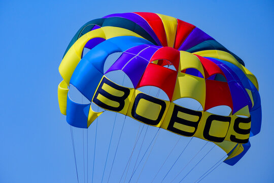 Vibrant multicolored parasail soaring against bright blue sky
