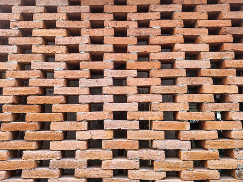Exposed brick wall featuring a perforated brick pattern that allows airflow and natural light, combining traditional craftsmanship with functional architectural design.