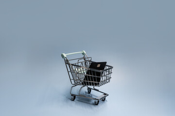 Miniature shopping cart with credit card on blue background for online shopping concept © Raphael