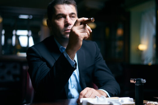 Handsome businessman starting smoking cigar in a bar