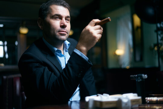 Handsome businessman starting smoking cigar in a bar