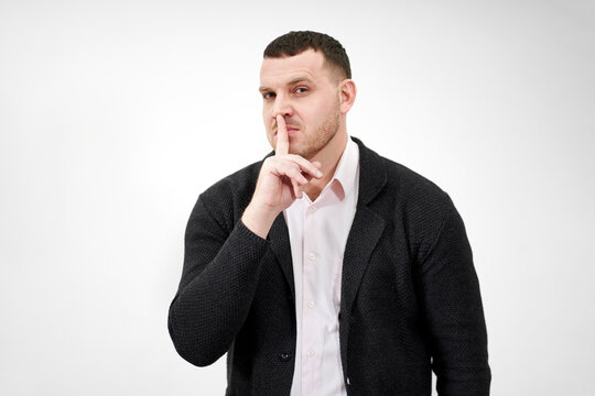 Man saying hush and be quiet with finger on lips gesture looking at camera