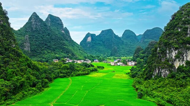 Aerial view of karst valley with green rice fields and a rural village surrounded by mountains in Guilin, China