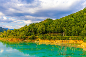 Obraz premium Landscape with artificial tailings pond at Geamana Flooded Village in the Apuseni Mountains of Alba County, Romania, dumping ground for toxic waste from the nearby Rosia Poieni copper mine