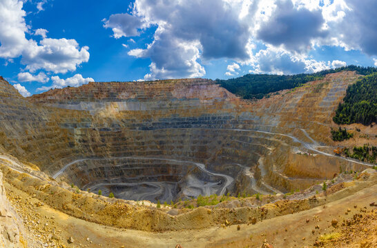 A massive open pit copper mine at Rosia Poieni in Alba County, Romania. Massive Terraced Open Pit Mine in the Apuseni Mountains. Human Impact on Nature, Giant Stepped Terraces of Surface Mining