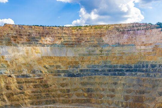 Steep, terraced benches of the Roșia Poieni copper mine, a massive open-pit excavation located in the Apuseni Mountains of Alba County, Romania.