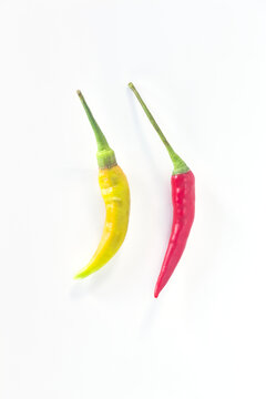 Yellow and red fresh chili peppers side by side on white background, vertical format