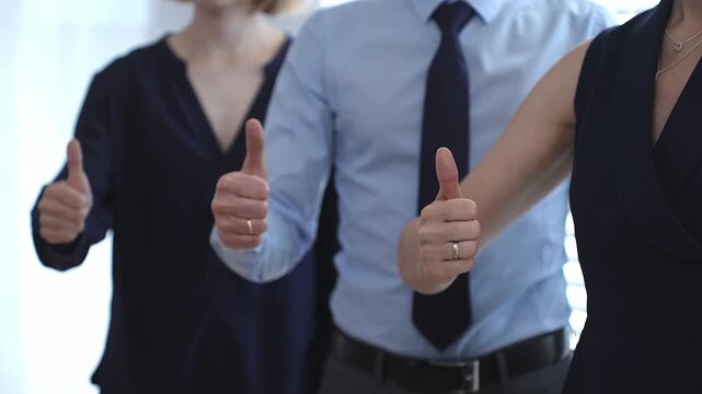 Business team showing thumbs up gestures in a row, expressing approval, agreement, success, and full support for a project or strategy in a corporate office setting