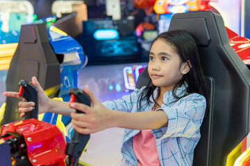 Young Asian girl playing a simulator arcade game. Family entertainment, recreation concept. © izzuan