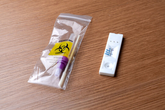 Positive Influenza A rapid antigen test cassette next to a sealed biohazard specimen bag containing a used swab. 
