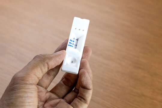 Hand holding a positive Influenza A rapid antigen test cassette. Viral infection, seasonal illness, and at-home medical care concept.