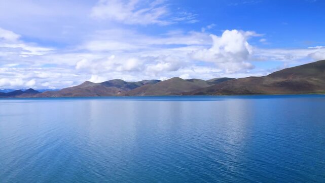 Yamdrok Lake, turquoise alpine lake and rolling mountain range under blue sky, Xizang China