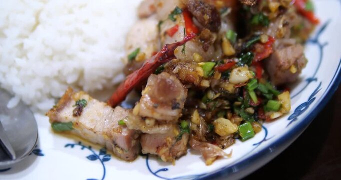 Close up of stir fried crispy pork belly with chili and garlic on rice