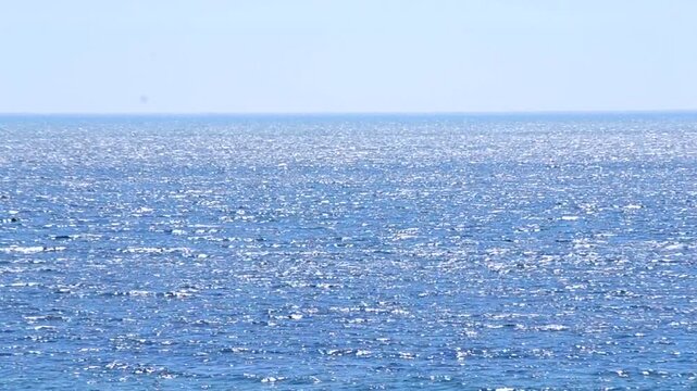 Seascape. Sea landscape on sunny day. Surface of blue sea with white sun glare and blue sky. View of blue sea with waves and white spots. Environment. Nature backdrop. Natural background. Nobody