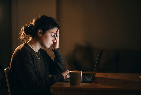 Woman exhausted at desk with coffee cup during late night work