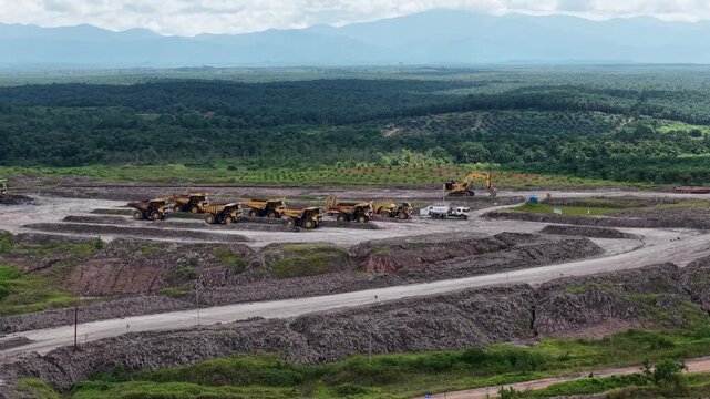 An aerial view of rigid dump trucks and excavators parked in a row at a coal mine