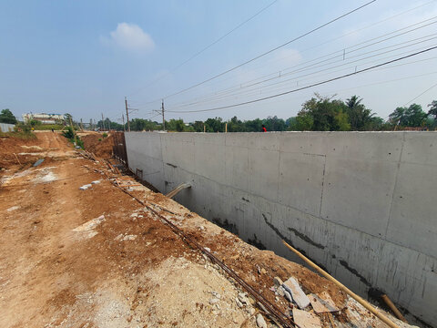 New concrete retaining wall construction site with dirt foreground.