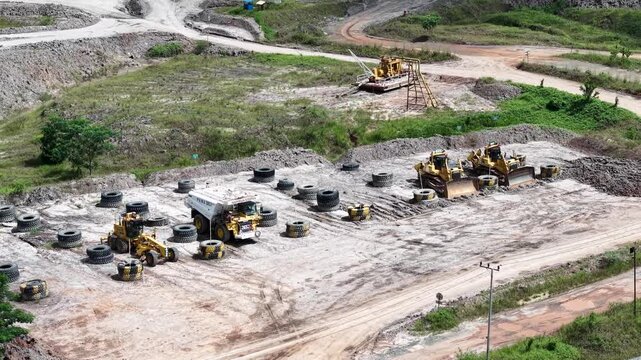 An aerial view of rigid dump trucks and excavators parked in a row at a coal mine