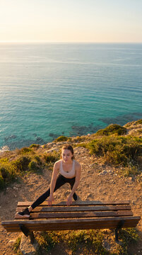 Woman standing on cliff edge overlooking turquoise ocean