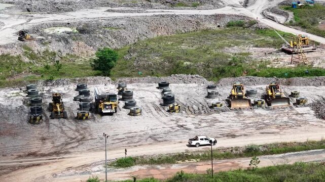 An aerial view of rigid dump trucks and excavators parked in a row at a coal mine