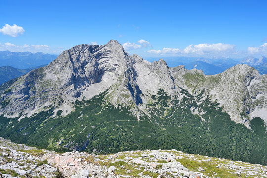 Alpine mountain range showing rocky peaks and green forests. Vast mountain landscape with rugged peaks and lush forests under a clear blue sky. Hochtor summit, Ennstaler Alps, Styria
