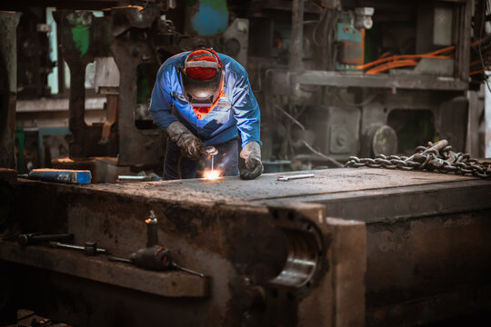 Industrial welder welding repair heavy construction in factory, Welding process by Shielded Metal Arc Welding (SMAW) or Stick Welding.