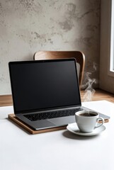 Fototapeta premium Laptop computer with blank screen placed on wooden surface beside a steaming cup of coffee in a cozy indoor setting with a chair and window in the background