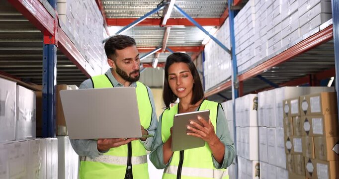 of Hispanic warehouse employees working on inventory control, counting boxes on shelves, using logistic application and database on tablet and laptop, discussing storage organization