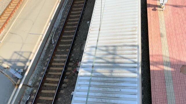 Overhead shot of railway platform beside moving cargo train wagon