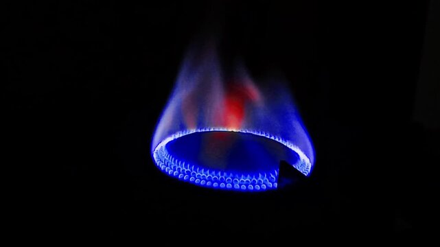 Bright blue and orange gas flame burning from a kitchen stove burner