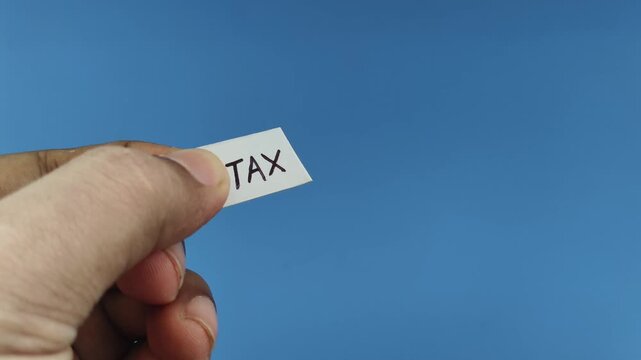 Closeup of hand holding white paper with tax benefit word or text written on it cut off using scissor. Burden of high business and personal income tax without any benefits to society concept.