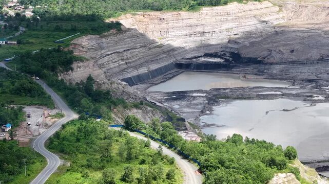 A drone view of a coal mine right next to the highway, featuring a very deep excavation pit.