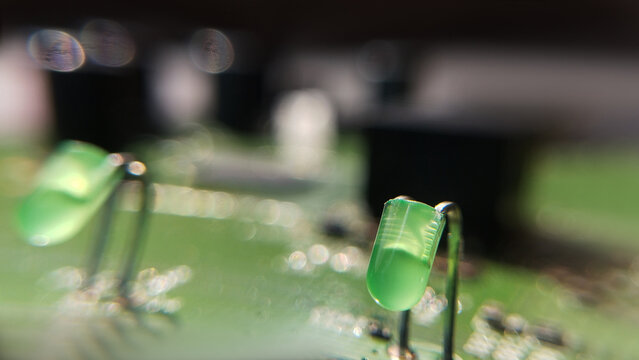 Macro look at green light emitting diodes attached to an electronic hardware board in a studio. led components, indicator bulbs, green electronics detail.
