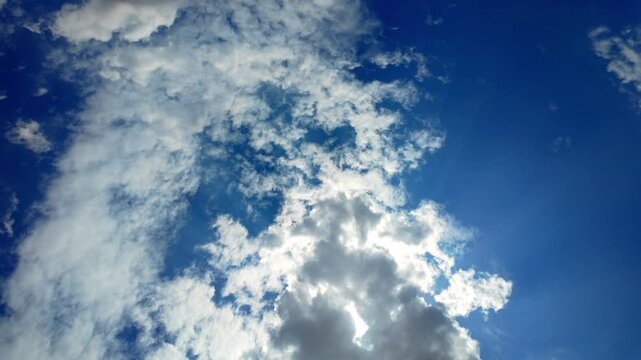 Sunburst Behind White Cumulus Clouds in Blue Sky