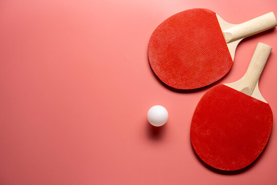 Ping pong rackets and balls on pink background, flat lay