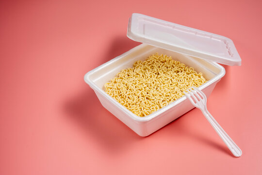 Instant noodles in styrofoam box on pink background