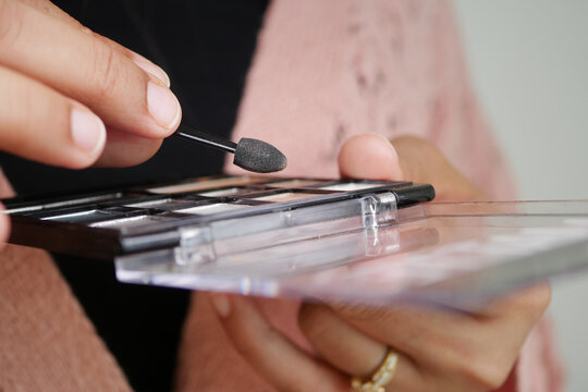 Applying makeup with a small tool from a palette