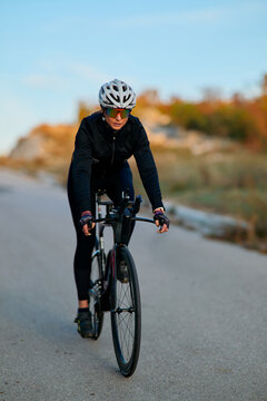 Female Cyclist Riding Road Bike Outdoors in Cycling Gear With Helmet and Sunglasses