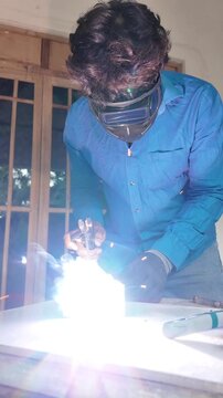 Metal fabrication worker welding steel while wearing protective safety equipment, capturing sparks and the skilled industrial manufacturing process.
