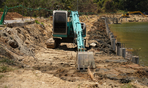 Building process city levee. Excavator dredging pond bank